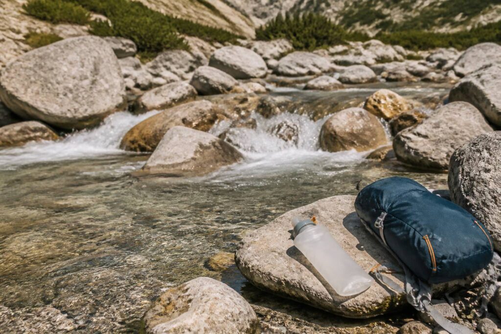 Gourde souple remplie à une source d'eau en montagne