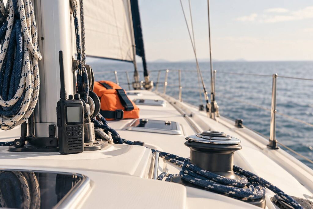 Radio VHF portable générique posée sur le pont d'un voilier en lumière du jour